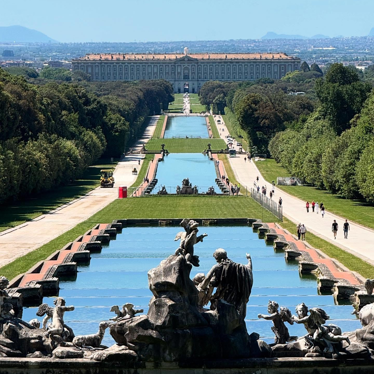 Panoramisch uitzicht op de tuinen van de Reggia di Caserta met fonteinen en lange waterbassins richting het paleis.